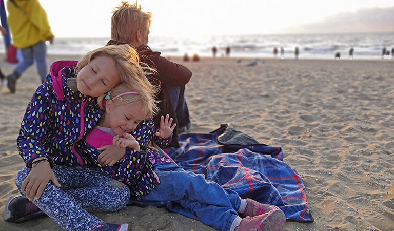 Kinder mit Windjacken und viel Spaß am Strand in den Niederlanden.