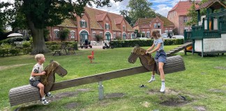 Erlebnisbauernhof an der Ostsee: Familienurlaub auf Gut Gaarz Kinder auf einer Pferdewippe vor dem Gzthaus des Gut Gare an der deutschen Ostseeküste.