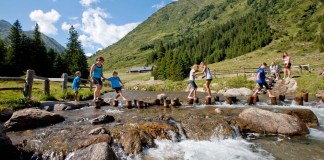 Die Region Murau mit Kindern entdecken: Familienurlaub in der Steiermark Kinder überqueren und spielen am Flusslauf des Eselsberger Almerlebniswegs in der Region Murau in der Steiermark in Oesterreich
