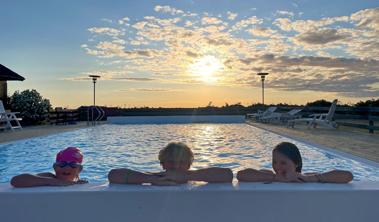 Familie im Pool der ferienhausanlage im Sonnenuntergang auf der dänischen Insel Bornholm.