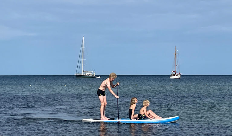 Kinder auf SUP am Strand von Bornholm.