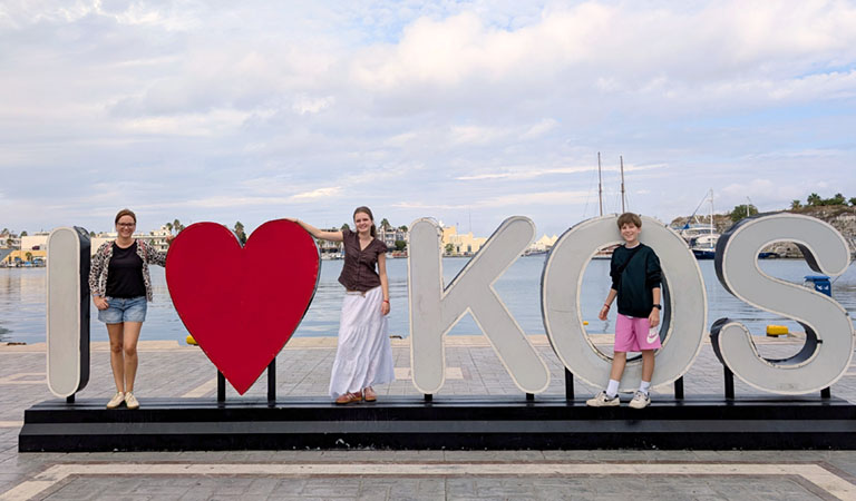 Familie posiert am I love Kos Schild in Kos Stadt auf der griechischen Insel Kos.