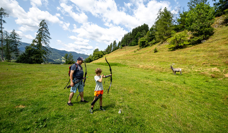 Vater und Sohn beim Bogenschiessen in der grünen Natur n der Region Murau in der Steiermark in Österreich