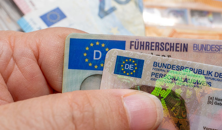Nahaufnahme von einem deutschen Führerschein und Personalausweis in einer Hand.