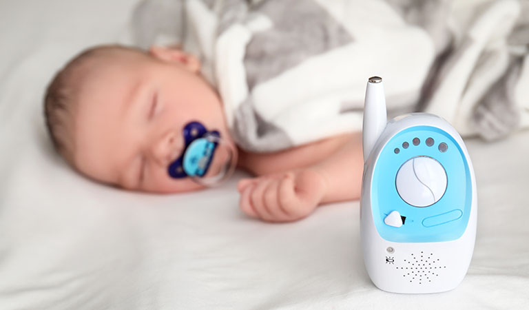Ein eingeschaltetes Babyphone vor einem schlafenden Kind – ein nützliches Reisegadget im Urlaub mit Baby und Kleinkind.