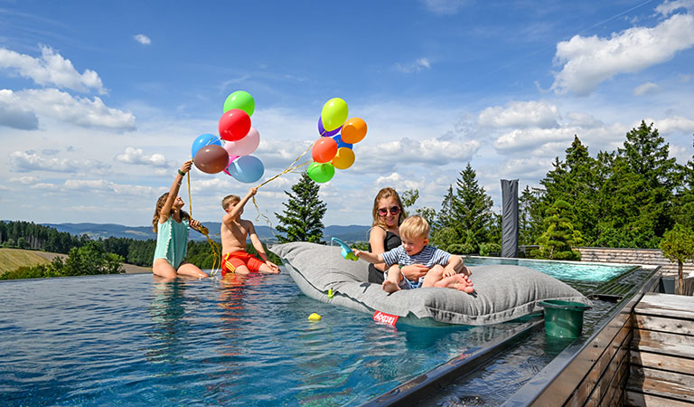 Familie beim Baden im Aussenpool des luxuriösen Kinderhotels Ulrichshof im Bayerischen Wald