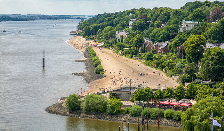 Lifbild über den weiten Strand von Oevelgönne an der Elbe in Hamburg mit der Strandbar Strandpele in der Entfernung.