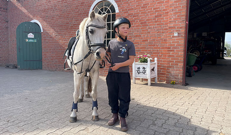 Junge mit seinem Pferd auf einem Reiterhof.