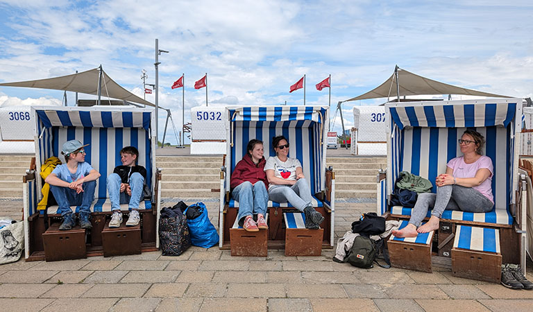 Familie sitzt in drei Strandkörben auf der Promenade von Büsum an der Nordseeküste
