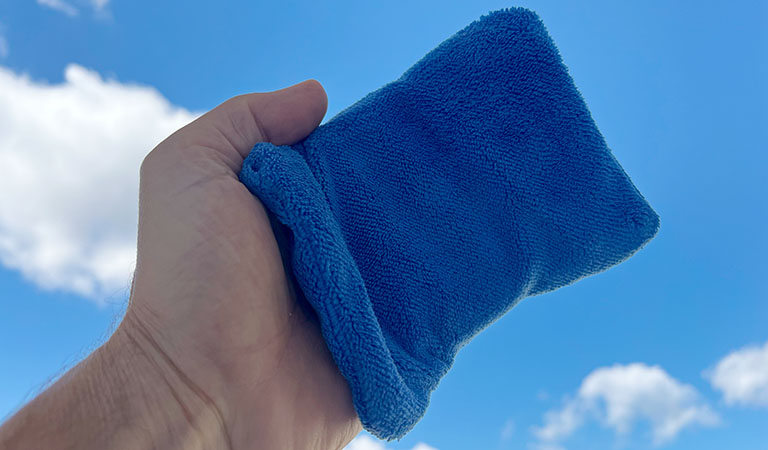 Ein blaues handschuhartiges Tuch zum entfernen von Sand auf der Haut, auch Sandentferner genannt.