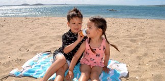 Kein Drama mehr beim Eincremen: Dieses Sommer-Gadget spart Eltern jeden Tag Nerven Junge und Mädchen am Strand beim eincremen mit einer der Solar Buddies Flaschen zum leichten eincremen mit Sonnencreme.