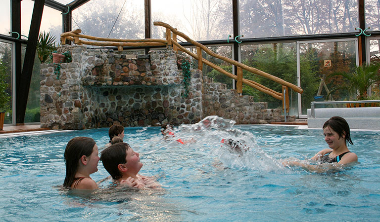 Indoor-Schwimmhalle mit spielenden Kindern im Ferienpark Geesthof in Niedersachsen in Deutschland.