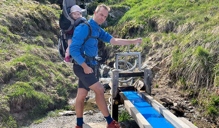 Vater mit Kindertrage am Easserspielplatz auf dem Berg Holm in Vorarlberg bei Montafon in Österreich.