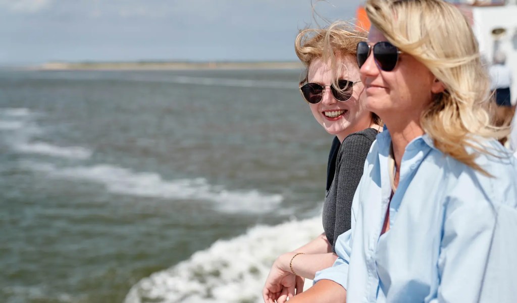 Zwei Frauen lehnen an der Reling der Fähre bei der Überfahrt auf die Insel Spiekeroog.