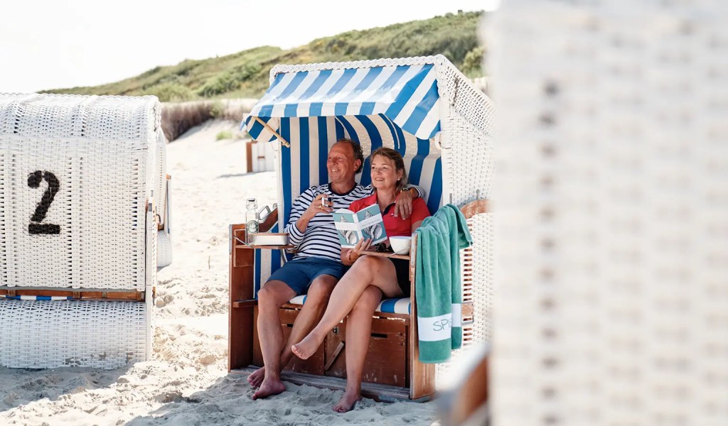 Ein Paar sitzt in einem Strandkorb am Strand auf Spiekeroog.