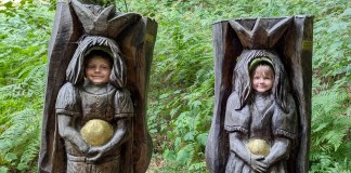 Eifel mit Kindern: Die schönsten Ausflugsziele zwischen Vulkanseen, Dinosauriern und Teufelsschlucht Zwei Kinder gucken durch die Löcher von zwei Baumfiguren in der Eifel.