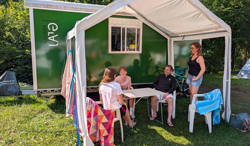 Familie sitzt vor ihrem Bauwagen im Familien-Sportcamp in Slowenien.