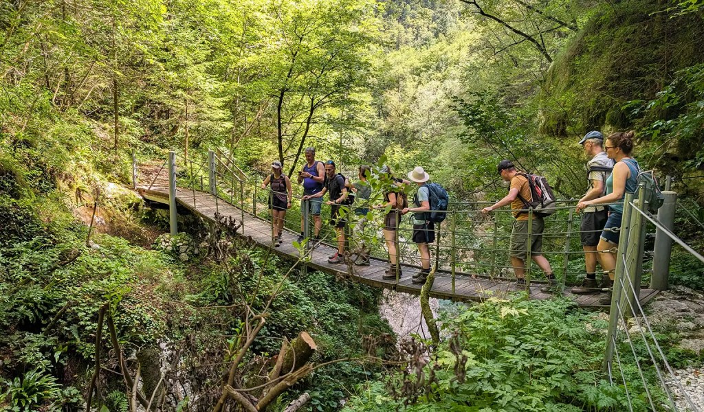 Eine Gruppe von Wanderern beim Überqueren einer Hängebrücke in Slowenien.