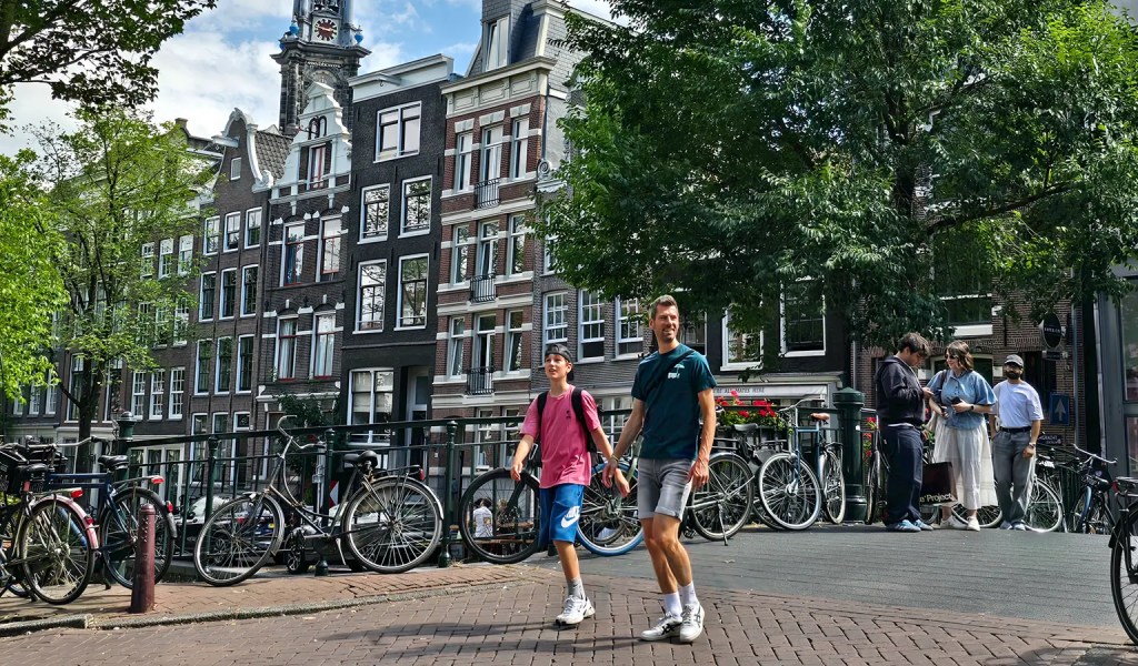 Vater und Sohn erkunden Amsterdam und gehen über eine der vielen Brücken.