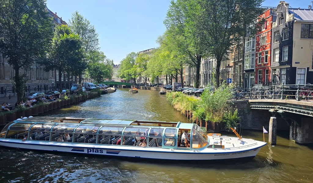 Blick auf ein Grachtenboot in einem Kanal in Amsterdam.