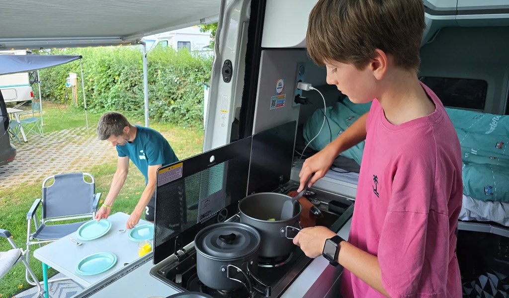 Ein Junge kocht im Roadsurfer-Camper.