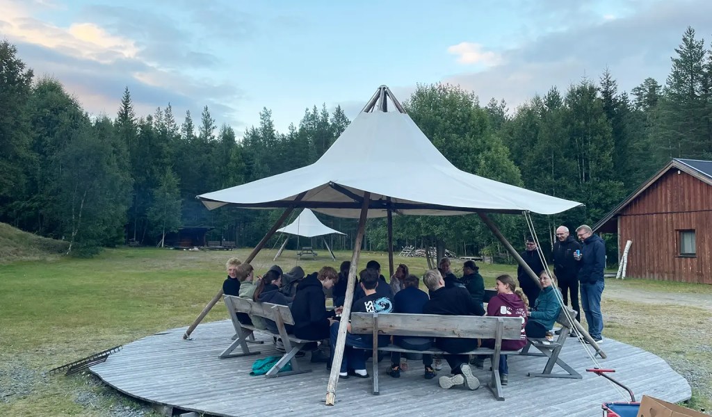 Gäste des Rucksack-Reisen-Camps Idre Stugor in Schweden am Lagerfeuer versammelt.